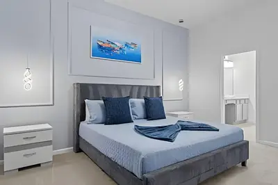 a white bedroom with a bed with blue pillows at Mansão 9Q Paradiso Grande. Piscina, Sala de Jogos in Orlando