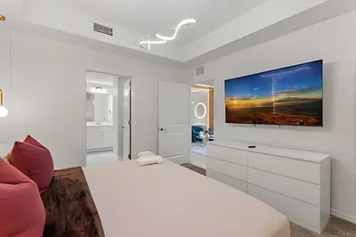 a white bedroom with a bed and a tv on the wall at Apto 2Q Storey Lake — Vista Lago e Clube in Kissimmee