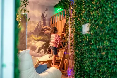 a young child climbing up a wooden stairs in a room at 10min to Disney, Luxury 6BR Themed Villa with Private Pool,Spa and Game Room in Orlando