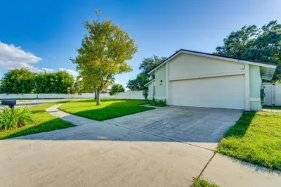 a house with a garage and a driveway at 3 Mi to SeaWorld! Suburban Home with Screened Porch in Orlando