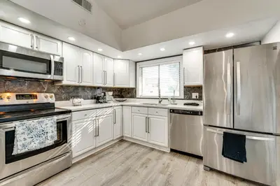 a kitchen with white cabinets and stainless steel appliances at 3 Mi to SeaWorld! Suburban Home with Screened Porch in Orlando