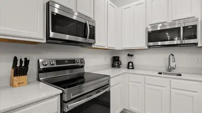 a kitchen with white cabinets and stainless steel appliances at Upstay Veranda Palms Villa Pool Hot Tub & Games in Kissimmee