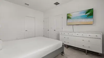 a white bedroom with a bed and a tv on the wall at Upstay Veranda Palms Villa Pool Hot Tub & Games in Kissimmee