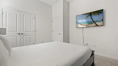 a white bedroom with a bed and a flat screen tv at Upstay Veranda Palms Villa Pool Hot Tub & Games in Kissimmee