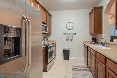 a kitchen with a stainless steel refrigerator and a clock on the wall at Apartamento 3Q no Vista Cay Resort in Orlando