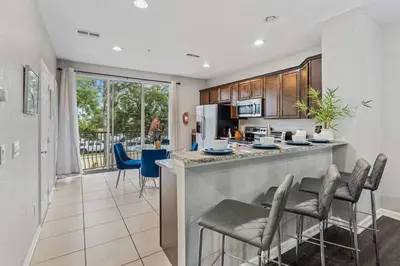 a kitchen and living room with a bar with chairs at Apartamento 3 Quartos Moderno no Vista Cay in Orlando