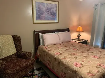 a bedroom with a bed and a chair and a lamp at Ortona's Best Kept Secret Three-Two Spacious Home in Orlando