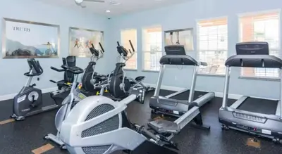 a gym with several treadmills and cardio machines at Stunning Townhome with Private Pool & Games Room in Orlando