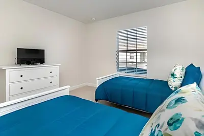 a bedroom with two blue beds and a tv at Villa Sanches 4Q c/ Piscina – Storey Lake Resort in Kissimmee