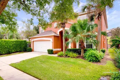 a house with a palm tree and a garage at Family Retreat near Disney with Private Pool in Kissimmee