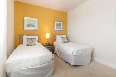 two beds in a room with yellow walls at Casa 3Q Serenity c/ Piscina – Perto da Disney in Orlando