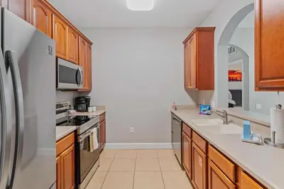 a kitchen with wooden cabinets and a stainless steel refrigerator at Apartamento 3 Quartos Amplo no Vista Cay Resort in Orlando