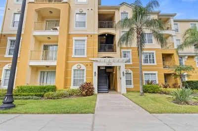 a yellow building with a palm tree in front of it at Apartamento 3 Quartos Amplo no Vista Cay Resort in Orlando