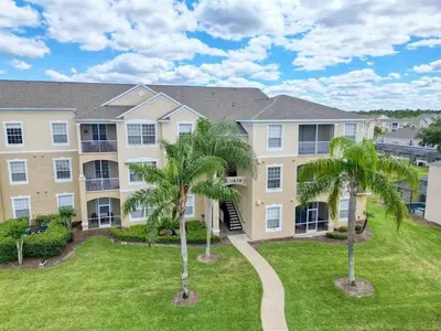 a large apartment building with palm trees in the yard at Condo 3Q Vista Cay c/ Varanda e Piscina Resort in Orlando