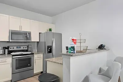 a kitchen with white cabinets and stainless steel appliances at Casa 3Q Moderna perto da Disney e acesso ao Resort in Kissimmee