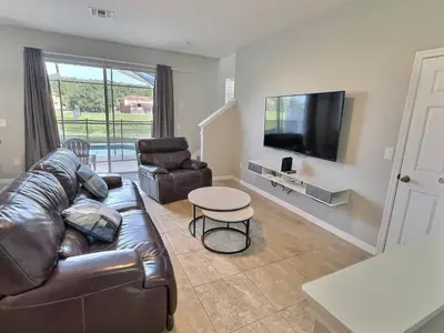 a living room with a leather couch and a television at Refúgio c/ Vista do Lago e Piscina – Perto Disney in Kissimmee