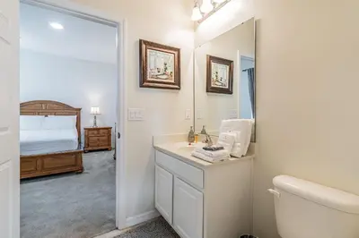 a bathroom with a sink and a toilet and a bed at Refúgio c/ Vista do Lago e Piscina – Perto Disney in Kissimmee