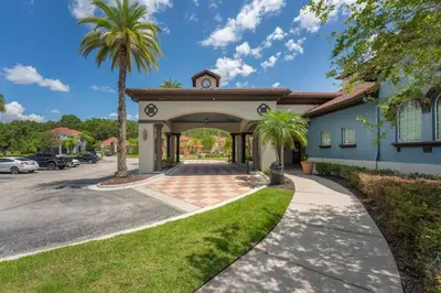 a building with a gate and palm trees at Refúgio c/ Vista do Lago e Piscina – Perto Disney in Kissimmee