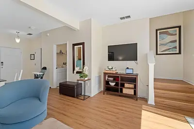 a living room with a blue chair and a television at Conforto e Diversão no Bella Vida – 3Q+ Piscina in Kissimmee