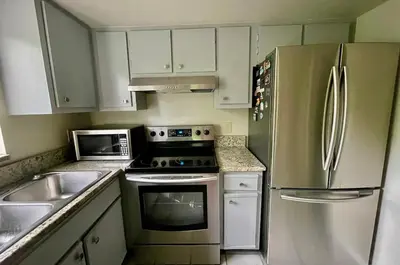 a kitchen with white cabinets and a stainless steel refrigerator at Residence near trails, shopping in Orlando