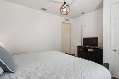 a white bedroom with a bed and a tv at Apartamento Vista Cay: ao lado do UNIVERSAL in Orlando