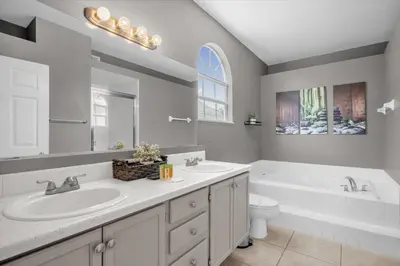 a bathroom with two sinks and a tub and a toilet at Disney Pool Retreat Modern Home Sleeps 8 in Kissimmee