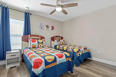 two beds in a bedroom with blue curtains at Cozy Pool Villa Minutes Drive to Disney in Orlando