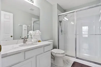 a white bathroom with a toilet and a shower at Cozy Pool Villa Minutes Drive to Disney in Orlando