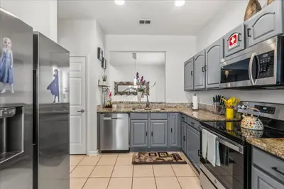 a kitchen with gray cabinets and stainless steel appliances at Large Family Retreat Pool BBQ Disney Parks Nearby in Orlando