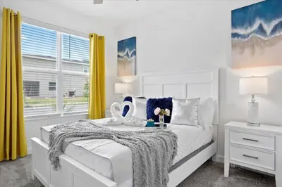 a bedroom with a bed with a white bedspread and yellow curtains at Bright Pool Villa Gated Resort Disney Shuttle Nearby in Kissimmee