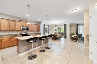 an open kitchen with bar stools and a living room at Disney Staycation Pool, Fun Resort Access in Kissimmee