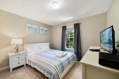 a bedroom with a bed and a desk with a television at Disney Staycation Pool, Fun Resort Access in Kissimmee