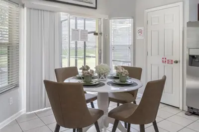 a white dining room with a white table and chairs at Bright Resort Home Pool Near Disney in Orlando