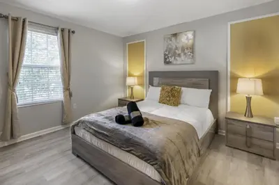 a bedroom with a bed and two lamps and two windows at Bright Resort Home Pool Near Disney in Orlando