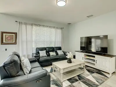 a living room with black leather furniture and a flat screen tv at Modern 6BR Resort Private Pool Near Disney in Orlando