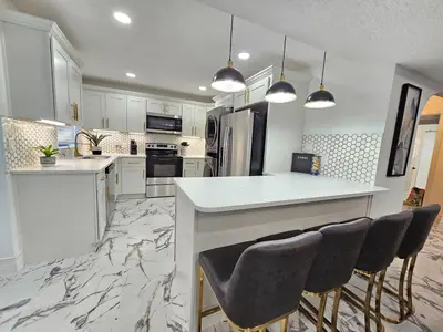 a kitchen with white cabinets and a island with bar chairs at Stylish Duplex walkTO Lake Eola Orlando. Sleeps 8 in Orlando