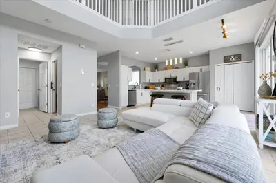 a living room with a white couch and a kitchen at Family-Friendly 6-Bedroom Villa with Pool Game Room and Themed Bedrooms at Emerald Island Resort in Kissimmee