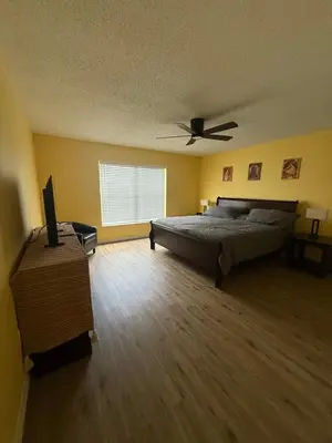 a bedroom with a bed and a ceiling fan at Sunny Orlando Oasis - Cozy 2 Bedroom house near Disney in Kissimmee