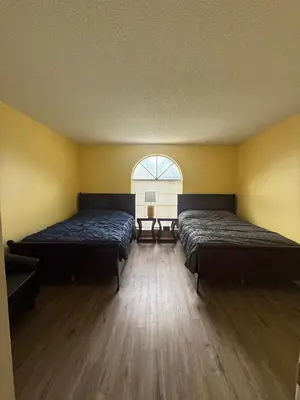 two beds in a room with a window at Sunny Orlando Oasis - Cozy 2 Bedroom house near Disney in Kissimmee