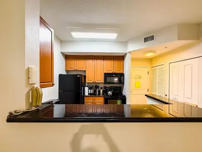 a kitchen with wooden cabinets and a black refrigerator at Flats moderno 4min da Universal - The Point Orlando in Orlando