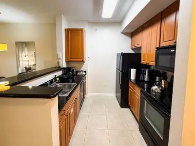 a kitchen with black appliances and wooden cabinets at Flats moderno 4min da Universal - The Point Orlando in Orlando