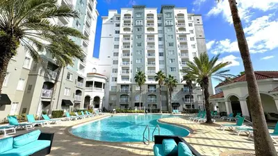 a large building with a swimming pool and palm trees at Flats moderno 4min da Universal - The Point Orlando in Orlando