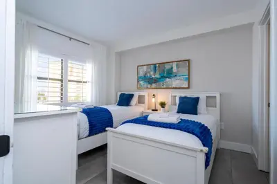 two beds in a white room with blue sheets at Modern 2BR Near Universal in Orlando