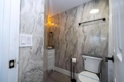 a bathroom with a toilet and a marble wall at Modern 2BR Near Universal in Orlando