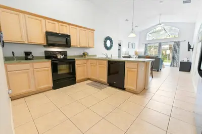 a large kitchen with wooden cabinets and black appliances at Elegant Emerald Island – Near Disney in Kissimmee