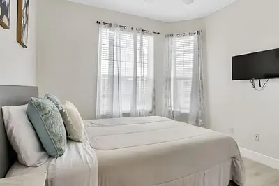 a white bedroom with a bed and a flat screen tv at Refúgio 3Q no Windsor Palms Resort in Kissimmee