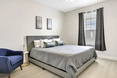 a bedroom with a bed and a blue chair at Refúgio 3Q no Windsor Palms Resort in Kissimmee