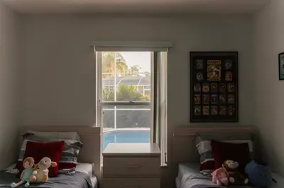 two beds in a bedroom with a window and teddy bears at 15 Mins Disneyworld Private Pool & Game Room in Kissimmee