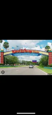 a car driving down a road under a large sign at 10 min to Disney | Karaoke | Game in Kissimmee