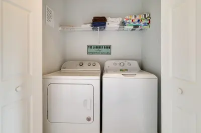 a small laundry room with two washers and a shelf at Family-Friendly Resort Getaway 5 Mi to Disney! in Kissimmee